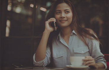 female sitting in a coffee shop with a cup of coffee talking on mobile phone